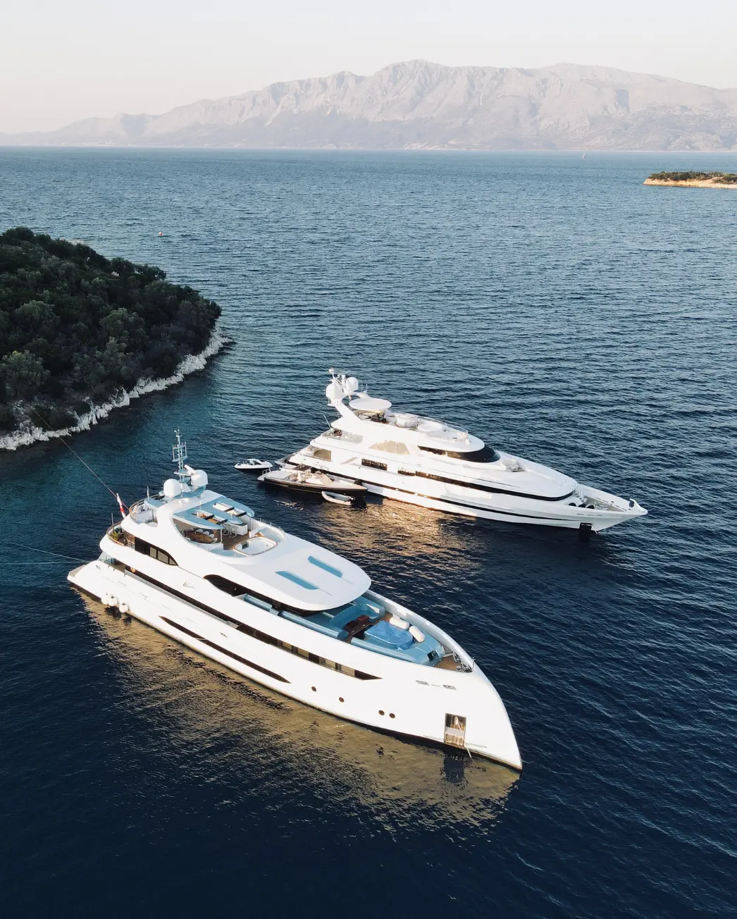 Two yachts sailing in the sea next to an island